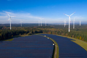 Solar power plant and wind turbines in a forest, aerial view